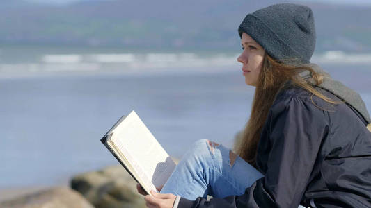年轻的妇女放松, 而读一本书的性质