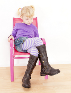小女孩穿着靴子坐在椅子上