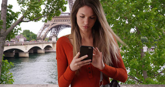 年轻女士拉着智能手机出来回复巴黎埃菲尔铁塔的短信