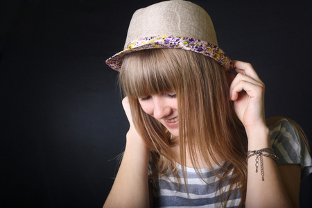 微笑的快乐的十几岁女孩笑保持她的帽子在室内