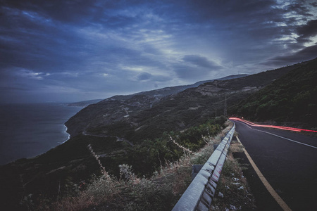 一条灯火通明的道路, 在长时间的照射下, 扭曲和弯曲了一座山。晚上车上有光迹的蜿蜒山路