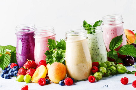 健康和有用的彩色浆果 cokctalis, 果汁和奶昔与酸奶, 新鲜水果和浆果在灰色桌上, 选择性聚焦