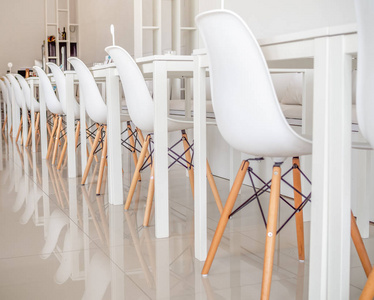 白色咖啡馆或餐厅内的白家具。一排白色木椅, 桌子和沙发上的清洁瓷砖地板