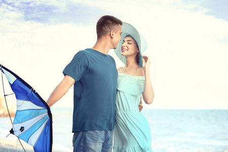 快乐年轻夫妇与风筝在海附近