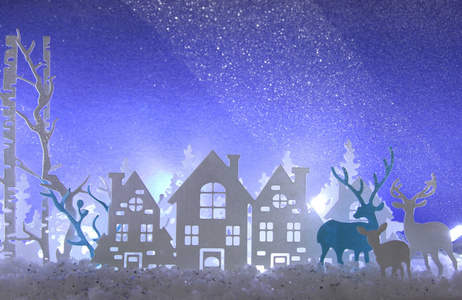 神奇的圣诞纸剪下冬季背景景观与房子, 树木, 鹿和雪在白色的灯光背景前