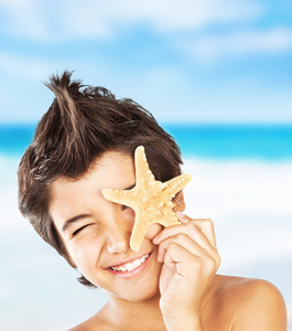幸福的脸男孩与海滩上的海星