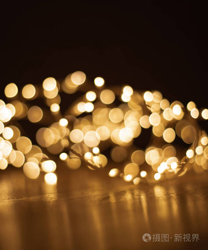 在黑暗的背景下, 昏暗的圣诞金色灯光.木地板上的圣诞花环, 抄写空间