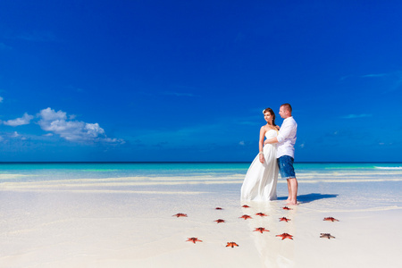 新郎和新娘站在热带海滩岸上与红 starfi