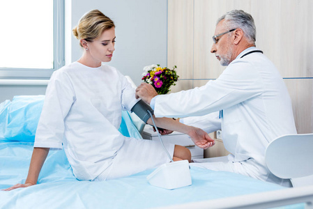 中年男性医生对医院病房女性病人手压力测量装置的侧面观察