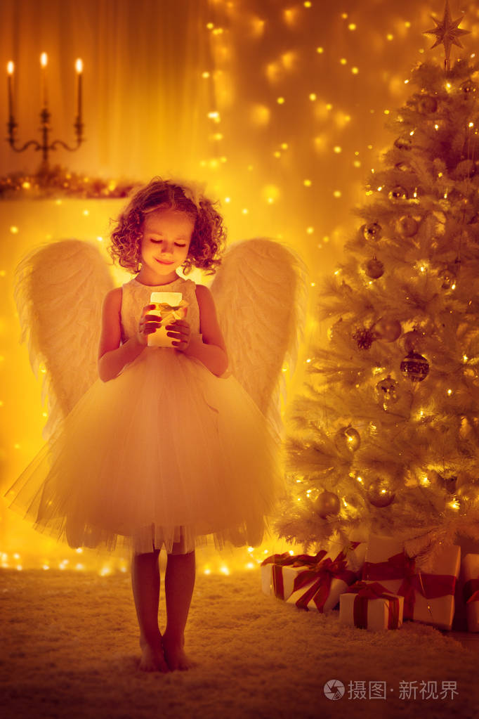 圣诞天使儿童与翅膀举行灯光蜡烛前的圣诞树, 新年之夜