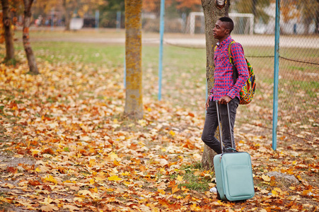 非洲裔美国人男子在格子衬衫, 手提箱和背包。黑人游客在秋季公园