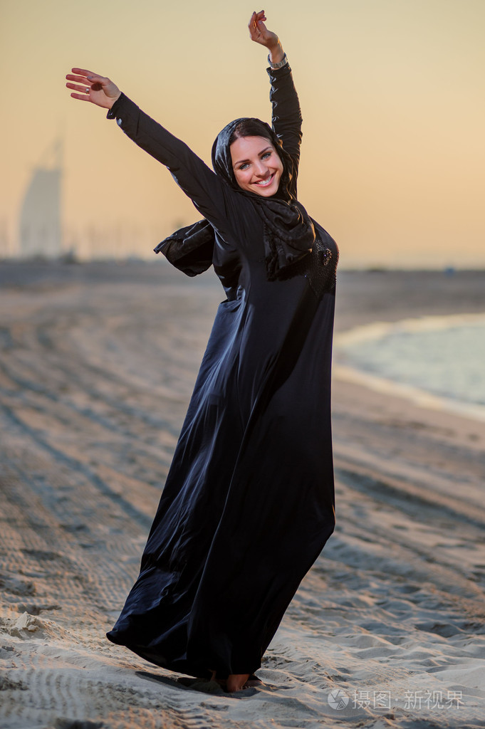 妇女穿中东方式构成上日落背景