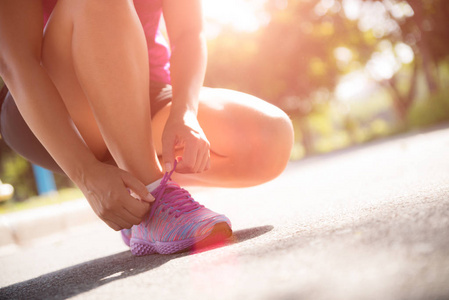跑鞋特写的女人绑鞋带。女子运动健身运动员准备在花园 backgroound 慢跑