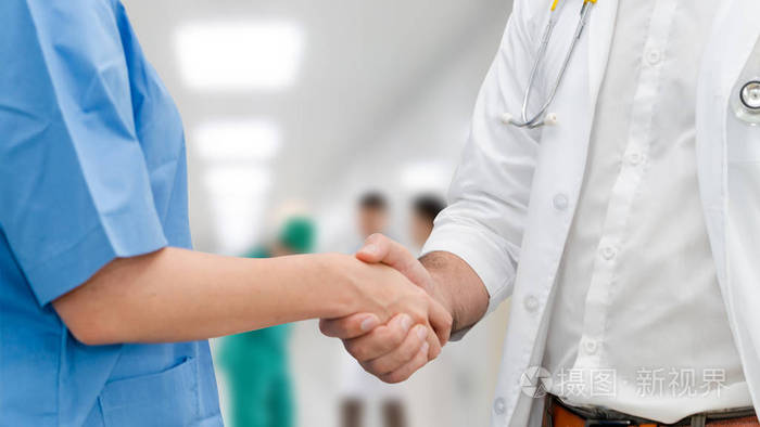 医生在医院与另一位医生握手.医护人员团队合作与医疗服务理念