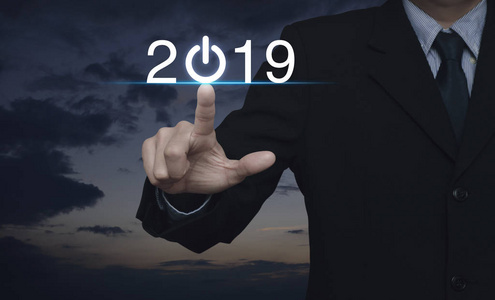 生意人按2019启动业务图标在夕阳天空, 新年快乐2019概念