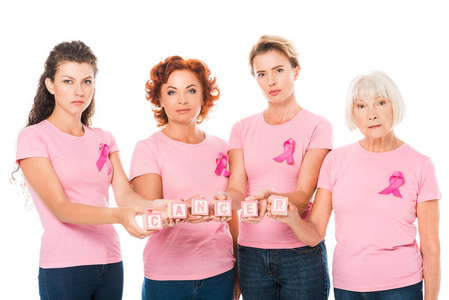 女性在粉红色 t恤与乳腺癌意识丝带持有立方体与词癌症, 看着相机在白色隔离