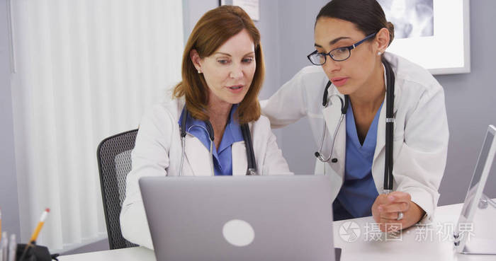 两位医生用笔记本电脑讨论病人的健康状况