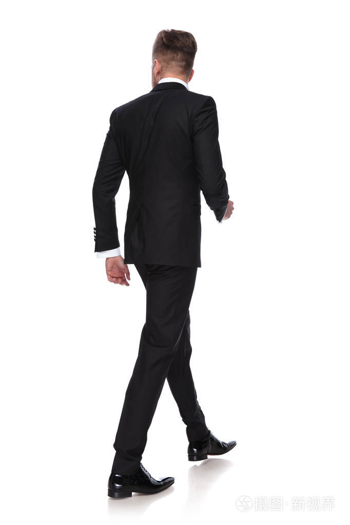 一个穿着燕尾服走路的年轻人的背视图在白色的背景