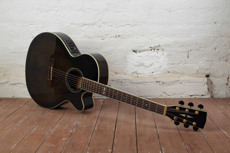 乐器褐色剖面声学吉他在砖的背景和木地板