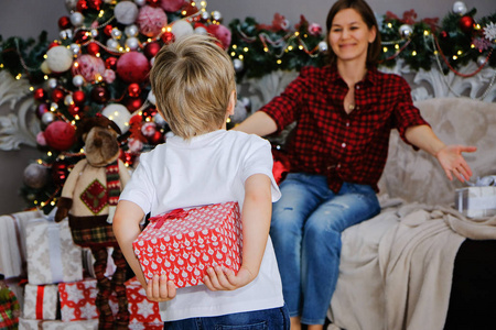 在家里的圣诞树附近, 带着礼物的母亲和孩子。家庭理念