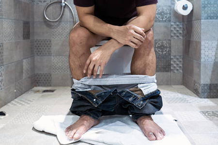 男子坐在坐便器上照片