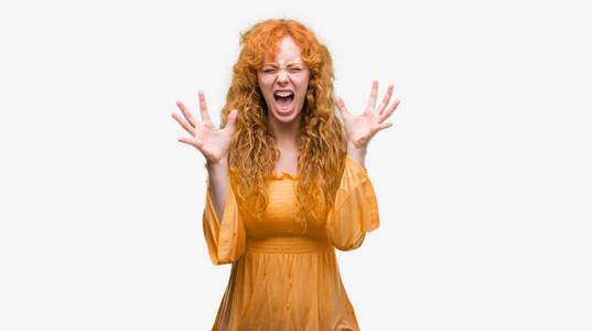 年轻的红发妇女庆祝疯狂和疯狂的成功与手臂举起和闭上眼睛尖叫兴奋