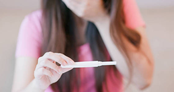 妇女采取怀孕测试和感到不安