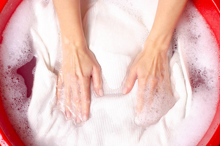 妇女在盆内灌肠粉末状洗涤剂中洗白色毛衣衣服