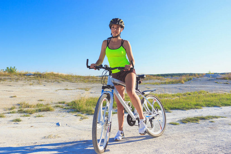 蓝色天空背景的年轻美丽的妇女与体育自行车