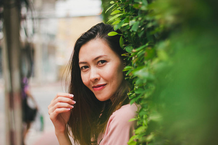 靠在一堵墙上的绿叶站立的女人