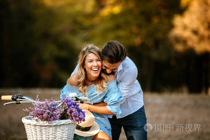 愉快的年轻夫妇共享一个拥抱而坐在自行车上