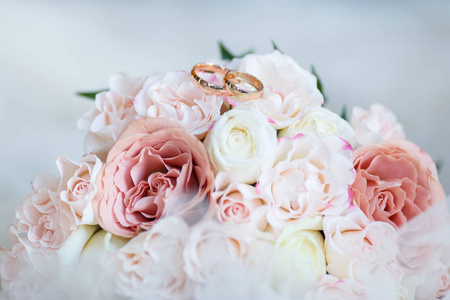 金色的结婚戒指躺在粉红色的玫瑰花蕾。结婚戒指躺在花蕾上