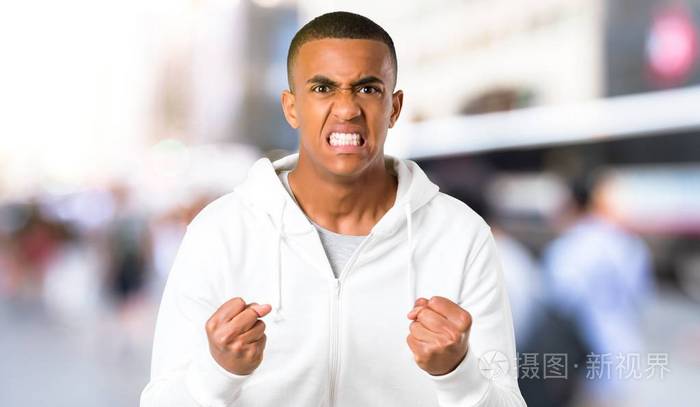 黑皮肤的穿白色运动衫的年轻人在愤怒的手势中生气了.