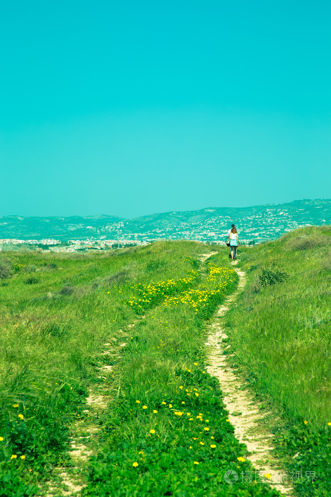 走在路上花黄色绿色草地上的人