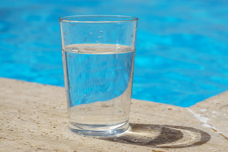 一杯干净的冷水在水池边用蓝色的水照片