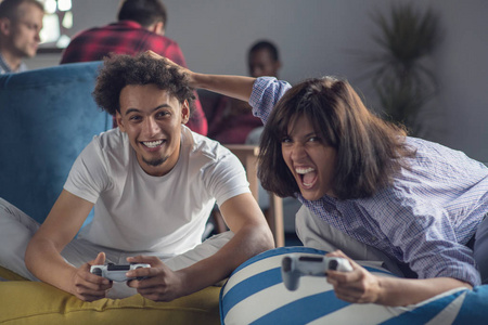 快乐的情侣玩电子游戏在现代启动办公室
