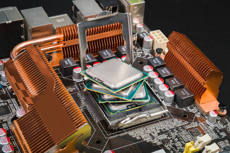 四处理器在主板插座中以风扇的形式位于其顶部, 黑色桌面上有橙色散热器。It 技术领域的进展