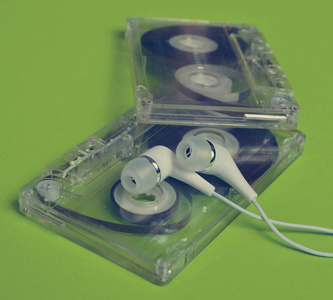 复古技术。塑料透明音频盒式磁带和白色真空耳机在明亮的绿色背景。80 年 代