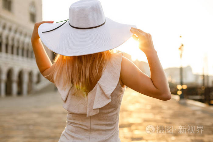 戴着帽子的年轻女士在一条老街上休息。女孩旅行到威尼斯