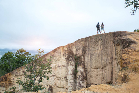 高山悬崖一对男女坐在悬崖上欣赏高山和云彩风景爱和旅行快乐情绪生活