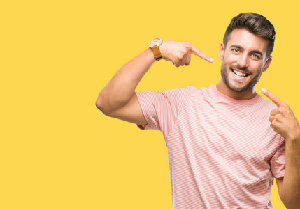 年轻英俊的男子在孤立的背景下微笑着自信地显示和指着手指的牙齿和