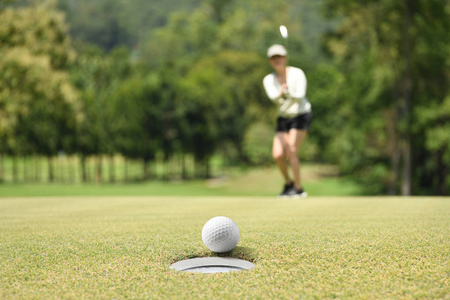 高尔夫绿色高尔夫球后的女子高尔夫球手欢呼