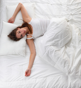 美丽的女孩睡在卧室里,躺在床上照片