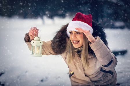 在美丽的冬天下雪天在户外举行圣诞彩灯的年轻女子