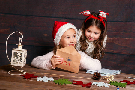 孩子给圣诞老人写信。滑稽的小女孩在圣诞老人帽子写信给圣诞老人