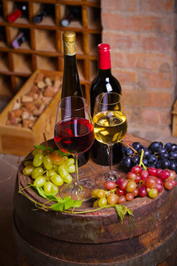 红酒窖里的老木桶上有葡萄的红白葡萄酒。酒杯和酒瓶