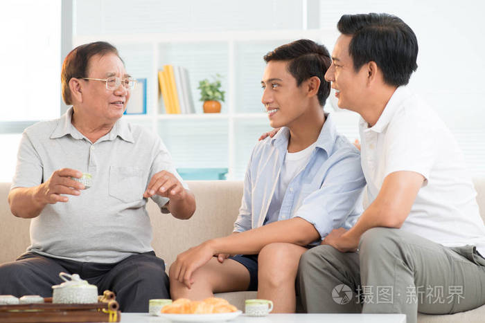 家中的亚洲家庭快乐的祖父与儿子和孙子交谈