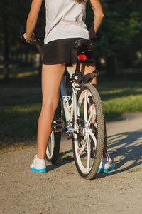 年轻运动妇女与自行车在日落, 软的焦点背景