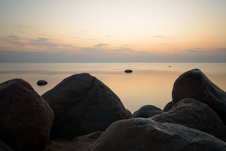大石头在海的背景在日落 tonted 与橙色。软焦点