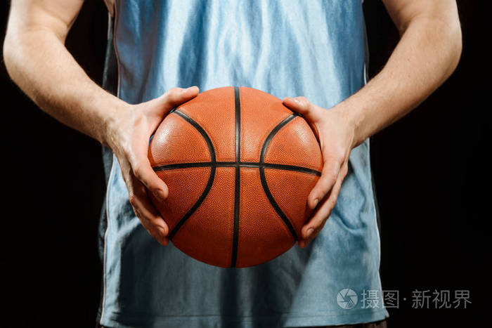 篮球手的球员在一个运动员举行的球特写镜头查出在黑色